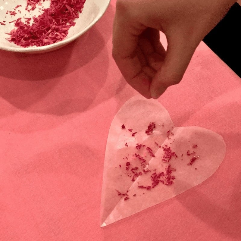 Your kids will enjoy sprinkling shredded crayons onto wax paper to create this Valentines Crayon Garland | WildflowersandWanderlust.com
