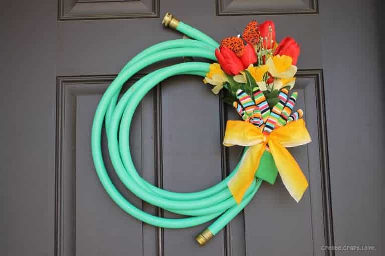 A water hose makes the perfect base for a spring wreath for your front door via Create Craft Love and showcased on WildflowersAndWanderlust.com